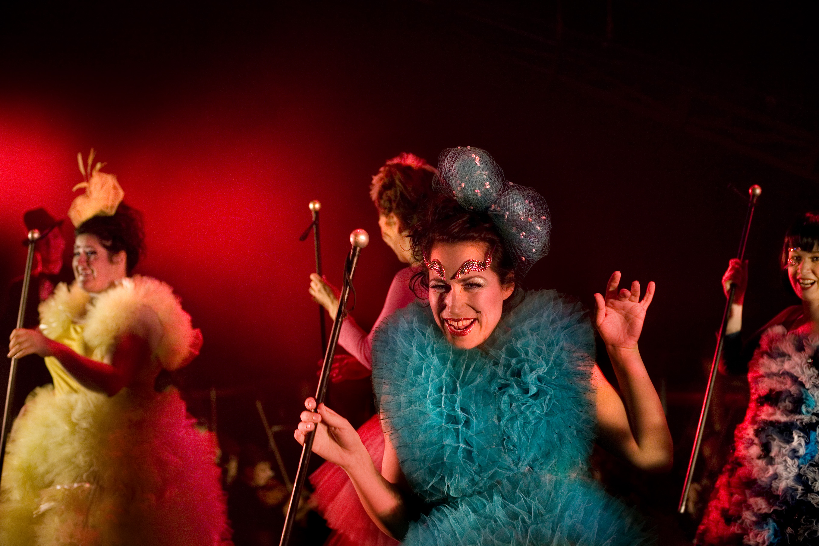 Fyra kvinnor klädda i färgstarka tyllklänningar dansar cabaret.