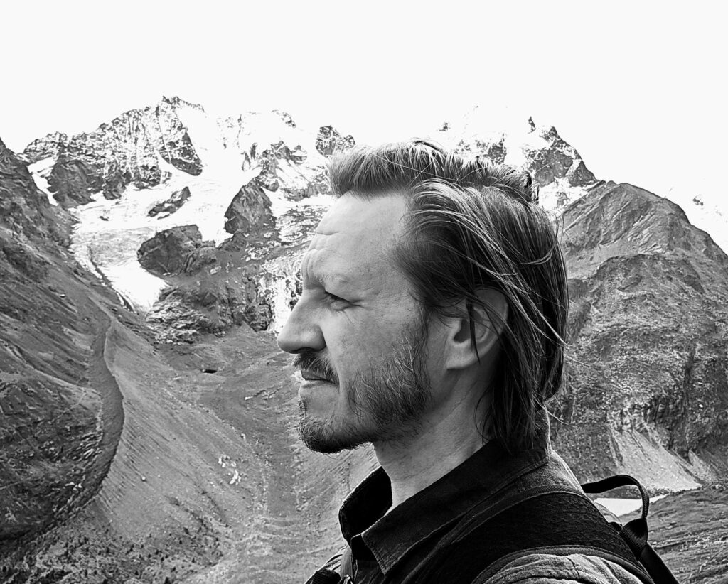 Joakim Sten står i profil framför alptopper. Foto: Privat.