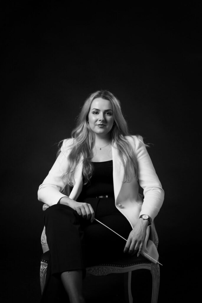 Elin Gripstrand sitter i en stol hållandes en dirigentpinne.